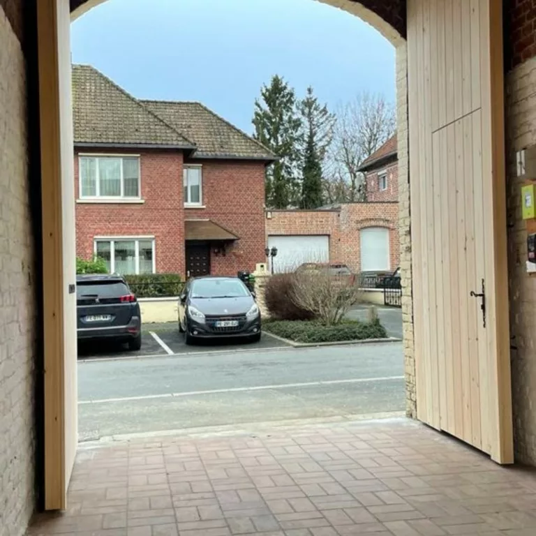 Porte cochère en bois clair arrondie, entrée voûtée, porte ouverte, vue sur la rue